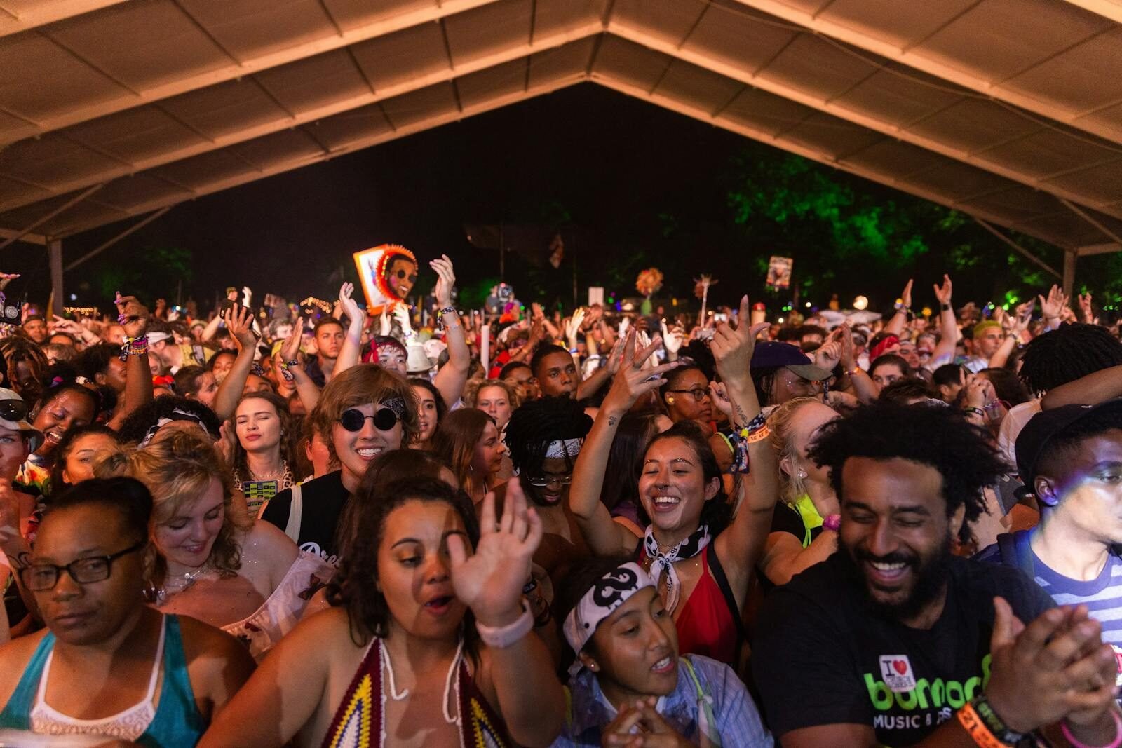 A lively night scene with a diverse crowd enjoying a music festival.